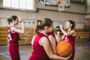 Twee meisjes omhelzen elkaar tijdens een basketbalwedstrijd